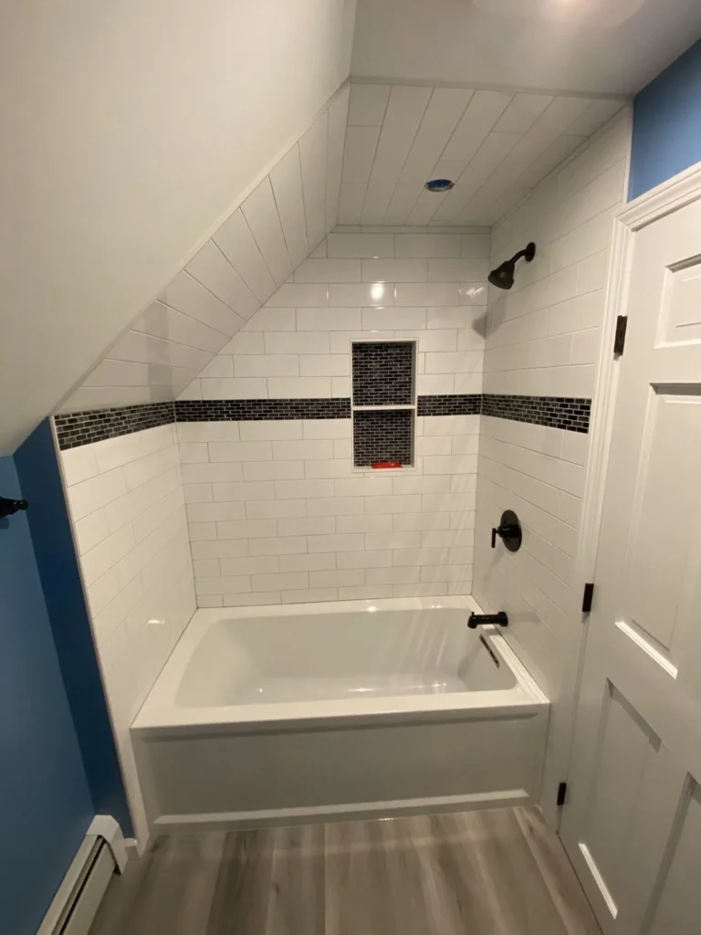 renovated bathroom with bathtub shower, white subway tile, black accent tile, recessed niche and matte black fixtures