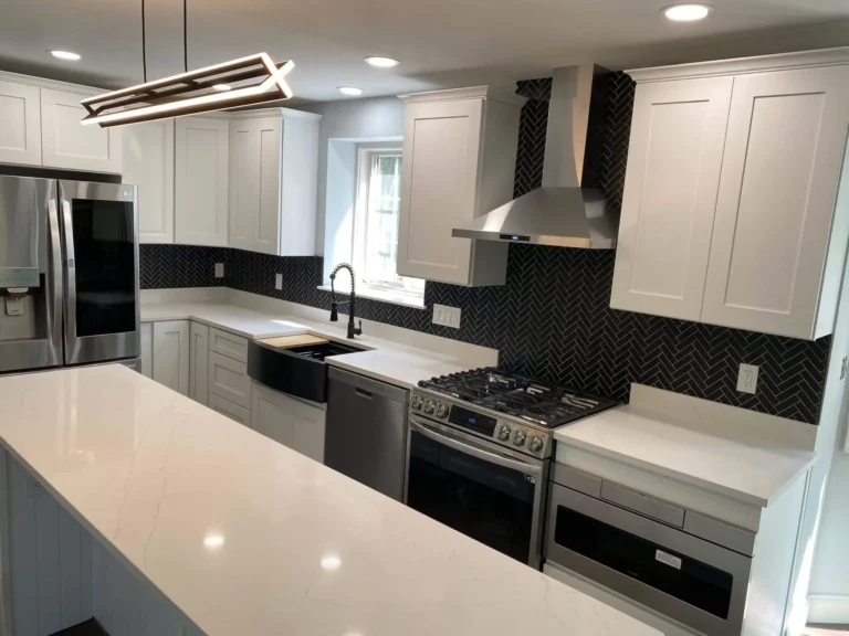 completed kitchen renovation with gray shaker cabinets, white quartz countertops, tile flooring, black appliances and peninsula cabinetry